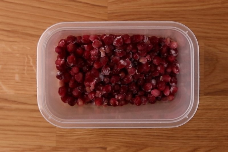 Frozen pomegranate seeds in a container