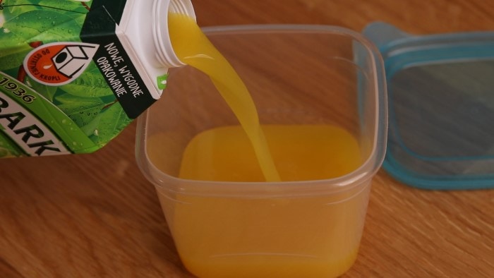 Verter jugo de naranja en un recipiente.