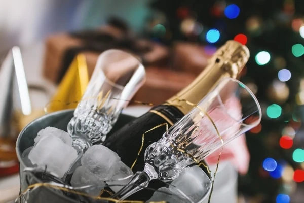 Botella de champan y dos copas en un cubo lleno de hielo