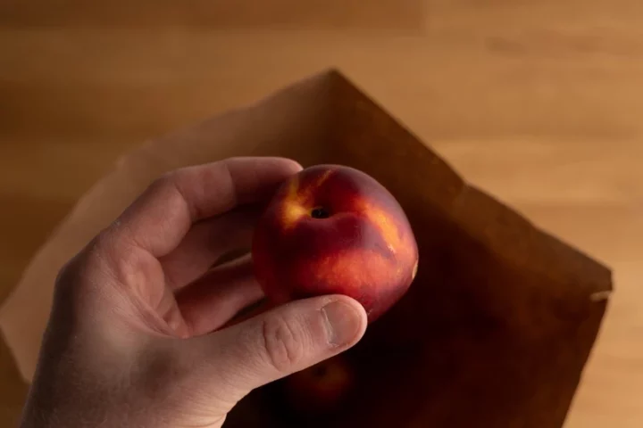 Placing nectarines in a brown bag to ripen