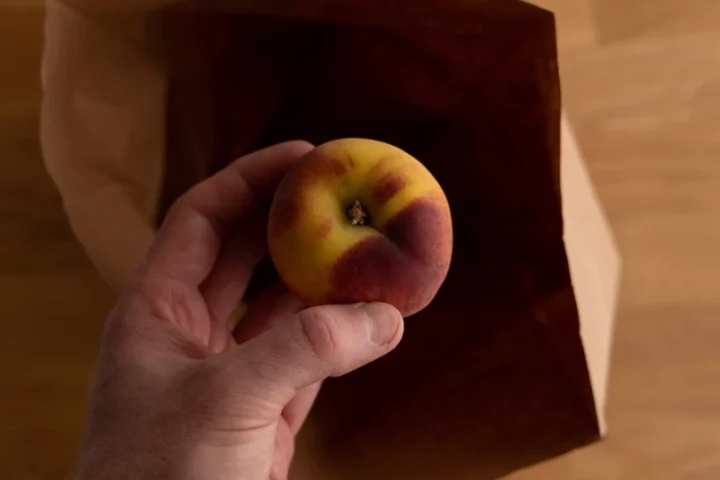Place the peach in the brown bag