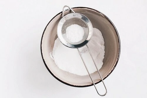 Baked powdered sugar in a strainer