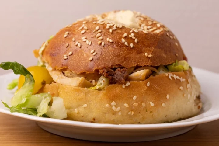 Sandwich de bagel con lechuga pollo y salsa