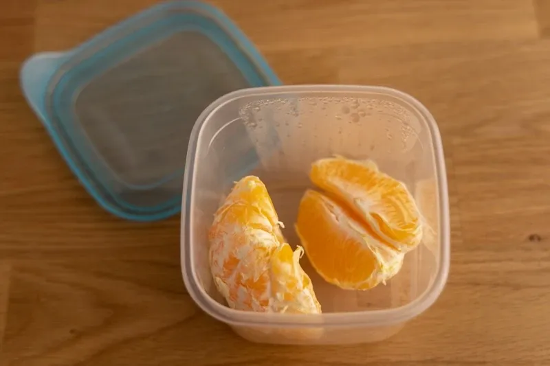 gajos de naranja pelados en un recipiente hermetico